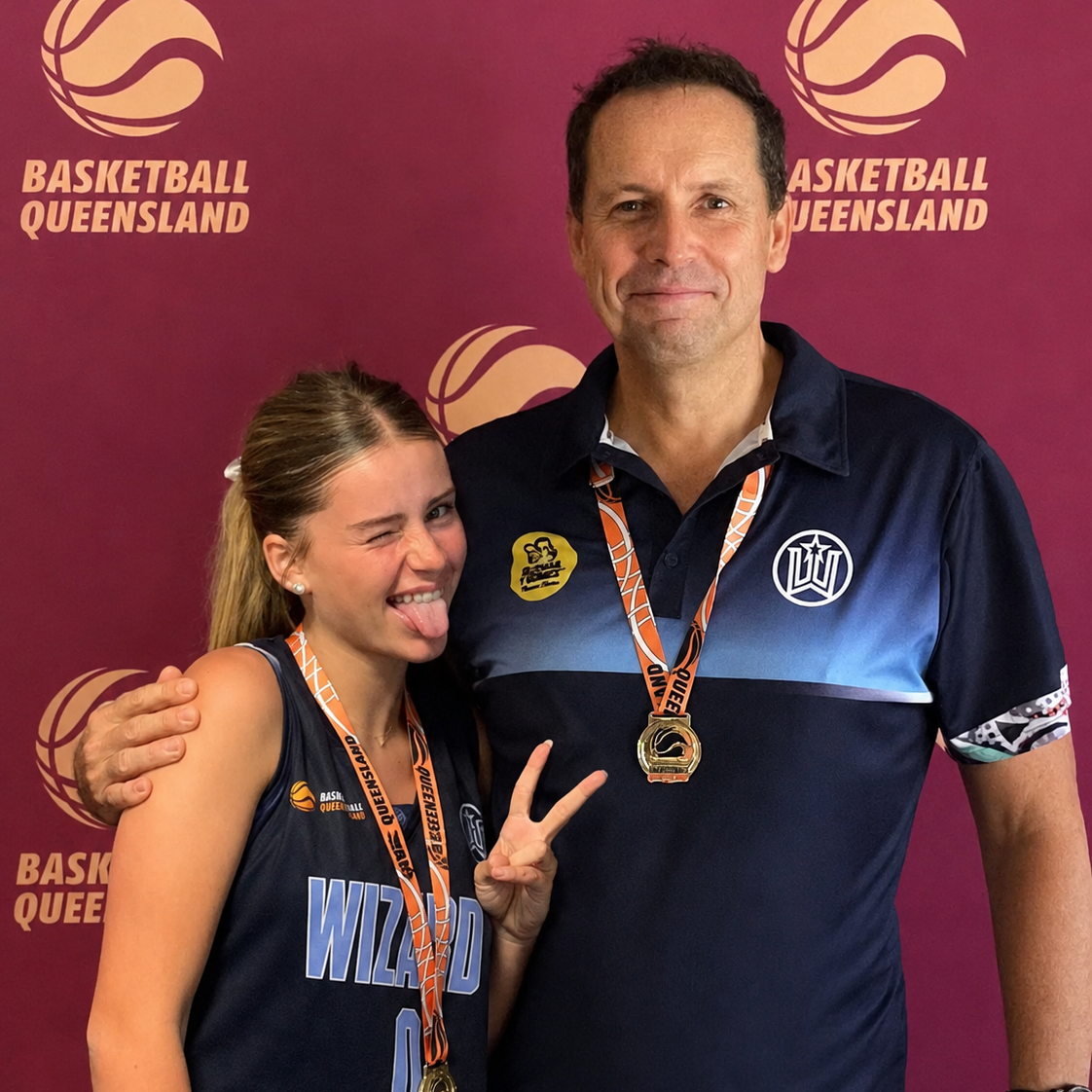 Two people posing together with basketball-themed background